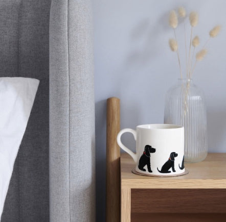 White ceramic mug with a black spaniel on it.